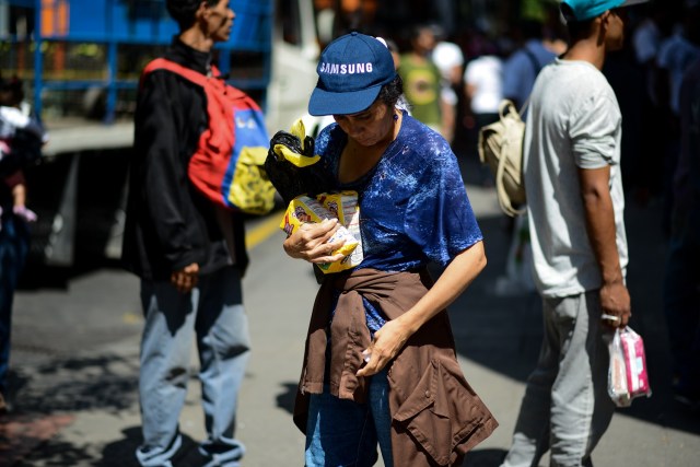 A woman holds two bags of flour after queuing outside a supermarket in Caracas to buy basic foodstuffs and household products on November 10, 2017. In crisis-stricken Venezuela, the cost of the basic basket of goods soared to nearly 2.7 million bolivars in September, the equivalent of six minimum monthly wages. / AFP PHOTO / FEDERICO PARRA