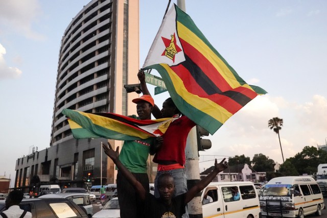People holding Zimbabwean flags celebrate in the street after the resignation of Zimbabwe's president Robert Mugabe on November 21, 2017 in Harare. Car horns blared and cheering crowds raced through the streets of the Zimbabwean capital Harare as news spread that President Robert Mugabe, 93, had resigned after 37 years in power. / AFP PHOTO / Marco Longari