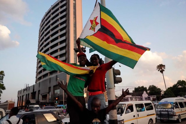 People celebrate in the streets after the resignation of Zimbabwe's president Robert Mugabe on November 21, 2017 in Harare. Car horns blared and cheering crowds raced through the streets of the Zimbabwean capital Harare as news spread that President Robert Mugabe, 93, had resigned after 37 years in power. / AFP PHOTO / Marco Longari