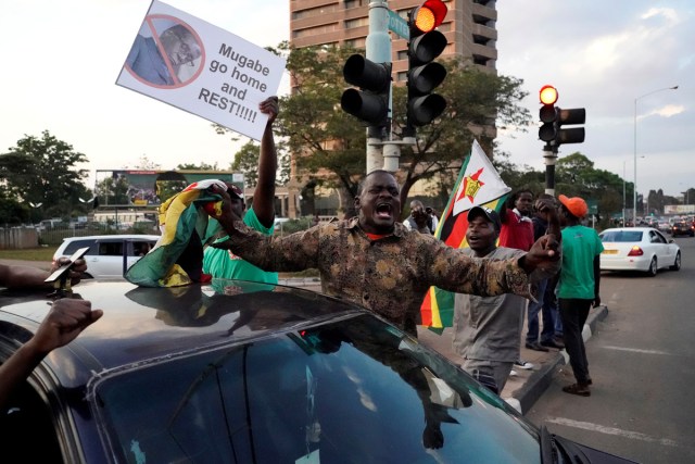 People celebrate in the streets after the resignation of Zimbabwe's president Robert Mugabe on November 21, 2017 in Harare. Car horns blared and cheering crowds raced through the streets of the Zimbabwean capital Harare as news spread that President Robert Mugabe, 93, had resigned after 37 years in power. / AFP PHOTO / Marco LONGARI