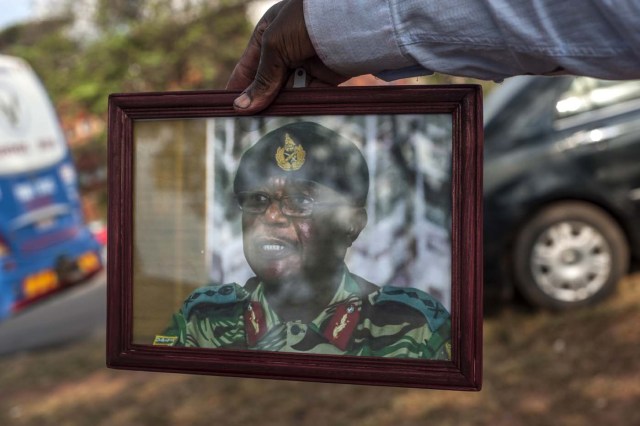 A supporter holds a portrait of Zimbabwe's Defence Force chief Constantino Chiwenga as supporters gather to welcome Zimbabwe's ousted vice president Emmerson Mnangagwa, at the headquarters of Zimbabwe's African National Union Patriotic Front (ZANU PF) party in Harare, on November 22, 2017. / AFP PHOTO / STEFAN HEUNIS