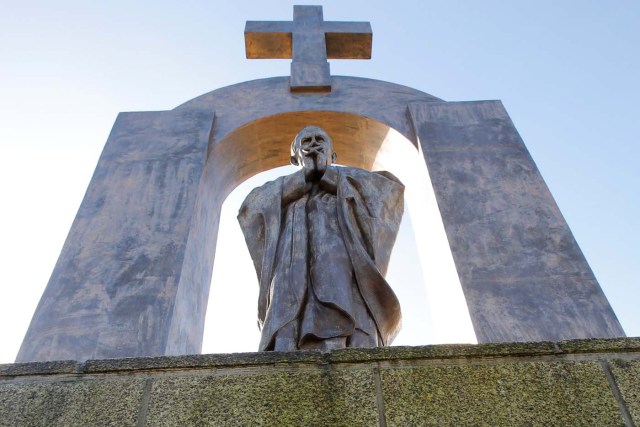 A statue of the late Pope John Paul II is seen under a cross in Ploermel, France, January 25, 2014. Picture taken January 25, 2014.    REUTERS/Stephane Mahe