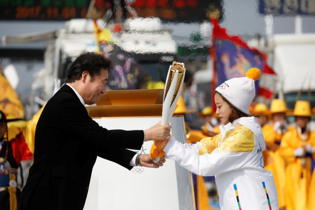 El primer ministro surcoreano, Lee Nak-yeon, entrega la antorcha olímpica al prospecto de patinaje artístico y el primer portador de la antorcha del país You Young en el puente Incheon en Incheon, Corea del Sur, el 1 de noviembre de 2017. REUTERS Kim Hong-ji