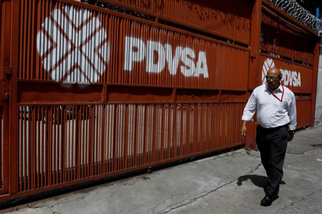 Un hombre camina delante de un logo de la petrolera estatal PDVSA en Caracas. Imagen de archivo. REUTERS/Marco Bello
