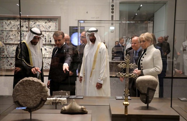 French President Emmanuel Macron (2ndL) and his wife Brigitte Macron (R) look at a piece of art as they visit the Louvre Abu Dhabi Museum during its inauguration in Abu Dhabi, UAE, November 8, 2017. Picture taken November 8, 2017. REUTERS/Ludovic Morin/Pool
