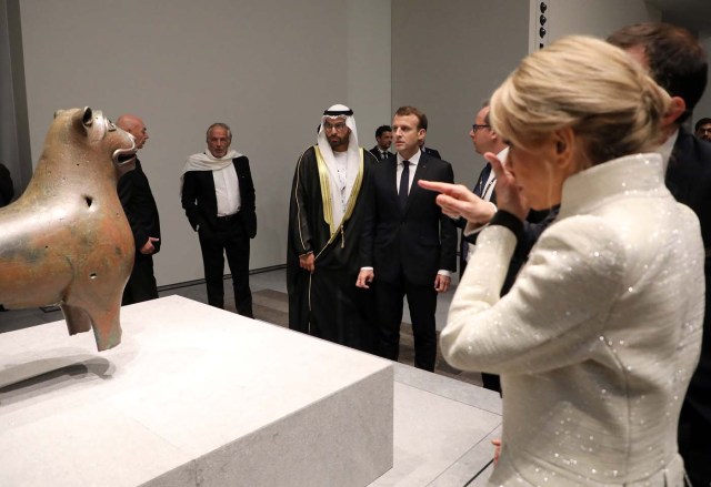 Brigitte Macron (R) reacts as French President Emmanuel Macron and Abu Dhabi's Tourism and Culture Authority, Mohamad Khalifa al-Mubarak look at art work as they visit the Louvre Abu Dhabi Museum during its inauguration in Abu Dhabi, UAE, November 8, 2017. Picture taken November 8, 2017. REUTERS/Ludovic Marin/Pool