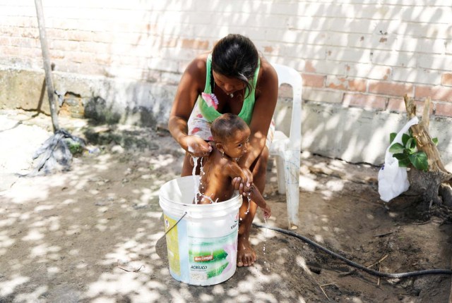 Indigenous Warao woman from the Orinoco Delta in eastern Venezuela, bathes her baby in a bucket at a shelter in Pacaraima, Roraima state, Brazil November 18, 2017. Picture taken November 18, 2017. REUTERS/Nacho Doce