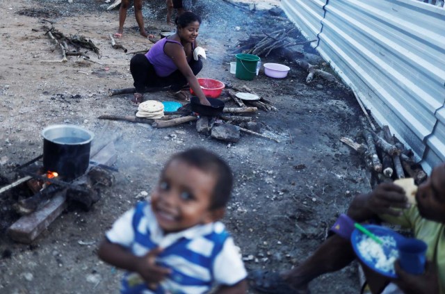 An indigenous Warao woman from the Orinoco Delta in eastern Venezuela, makes food next to her family at a shelter in Pacaraima, Roraima state, Brazil November 15, 2017. Picture taken November 15, 2017. REUTERS/Nacho Doce