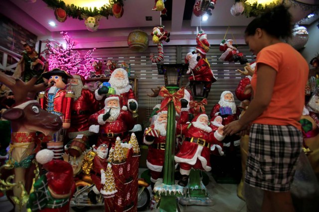 A worker cleans Santa Claus figurines on display while waiting for customers inside a shop in Metro Manila, Philippines November 28, 2017. REUTERS/Romeo Ranoco