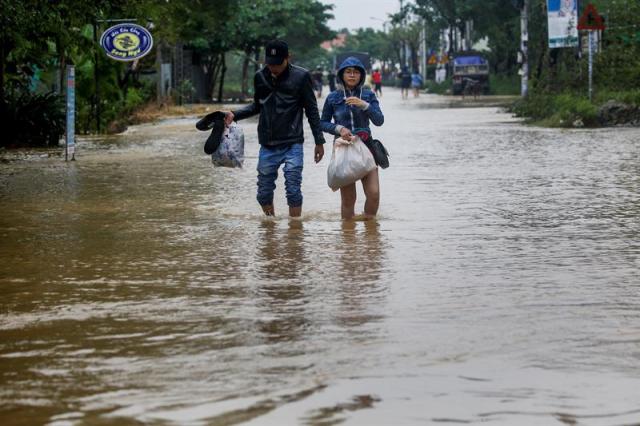 Residentes caminan por las calles inundadas de Hoi An (Vietnam) hoy, 6 de noviembre de 2017. Al menos 27 personas murieron y otras 22 se encuentran desaparecidas debido a las fuertes lluvias e inundaciones causadas por el tifón Damrey en la zona central de Vietnam. EFE/ Wallace Woon