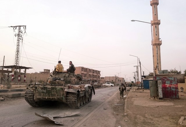 Members of the pro-Syrian government forces ride on a tank as it drives down a street in the Syrian border town of Albu Kamal, on November 20, 2017. Syria's army and loyalist militiamen Sunday ousted the Islamic State group from its last urban stronghold in the country as regime strikes claimed more lives in a rebel-held enclave near Damascus. The army said it had taken full control of Albu Kamal in the eastern province of Deir Ezzor, which has changed hands several times. / AFP PHOTO / STRINGER