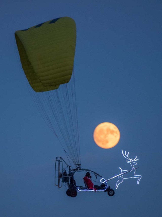 A man, disguised as Santa Claus, flies in a microlight past the Moon on December 2, 2017 near Sieversdorf, eastern Germany. / AFP PHOTO / dpa / Patrick Pleul / Germany OUT
