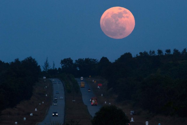 The supermoon rises over a highway near Yangon on December 3, 2017. The lunar phenomenon occurs when a full moon is at its closest point to earth. / AFP PHOTO / Ye Aung THU