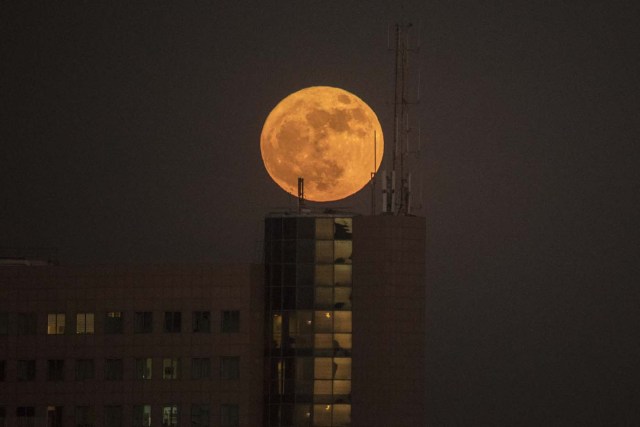The 'supermoon' rises over a building in the Israeli city of Netanya, on December 3, 2017. The lunar phenomenon occurs when a full moon is at its closest point to earth. / AFP PHOTO / JACK GUEZ
