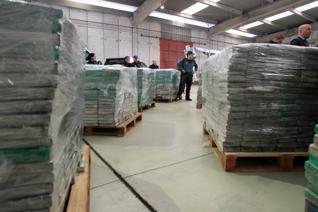 A guardia civil stands next to several piles of high-purity heroin blocks on December 5, 2017 at the Algeciras seaport, seized by Spanish police after founding it hidden in a shipment of cement that arrived from Turkey. Spanish police have seized 331 kilos (730 pounds) of heroin worth an estimated 120 million euros ($142.5 million), in one of the country's biggest-ever drug hauls, officials said on December 5, 2017.  / AFP PHOTO / STR /