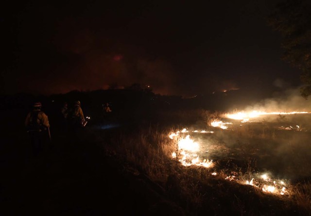 Firefighters light backfires as they try to contain the Thomas wildfire which continues to burn in Ojai, California, on December 9, 2017. Brutal winds that fueled southern California's firestorm finally began to ease Saturday, giving residents and firefighters hope for respite as the destructive toll of multiple blazes came into focus. / AFP PHOTO / MARK RALSTON