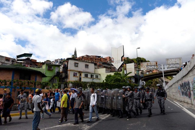 Riot police disperse demonstrators during a protest against the shortage of food in Caracas on December 28, 2017. As Venezuelans protest in Caracas demanding the government's prommised pork -the main dish of the Christmas and New Year's dinner-, President Nicolas Maduro attributes the shortage to international sabotage. / AFP PHOTO / FEDERICO PARRA