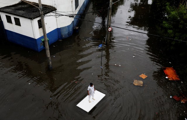 A worker uses a table to move along a flooded street after heavy rainfall in Sao Paulo, Brazil April 7, 2017. REUTERS/Nacho Doce/File Photo      SEARCH "POY GLOBAL" FOR THIS STORY. SEARCH "REUTERS POY" FOR ALL BEST OF 2017 PACKAGES.    TPX IMAGES OF THE DAY
