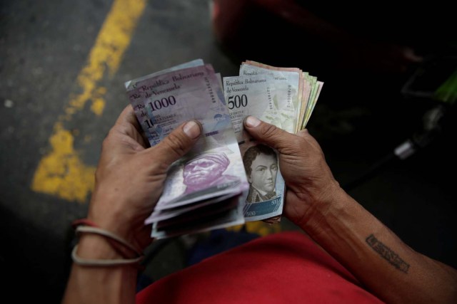 A worker counts Venezuelan bolivar notes at a gas station of Venezuelan state oil company PDVSA in Caracas, Venezuela December 1, 2017. REUTERS/Marco Bello