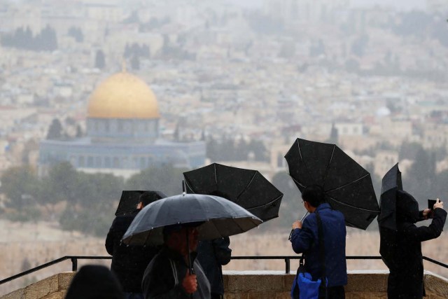 People hold umbrellas as it rains at an observation point overlooking the Dome of the Rock and Jerusalem's Old City December 6, 2017. REUTERS/Ammar Awad