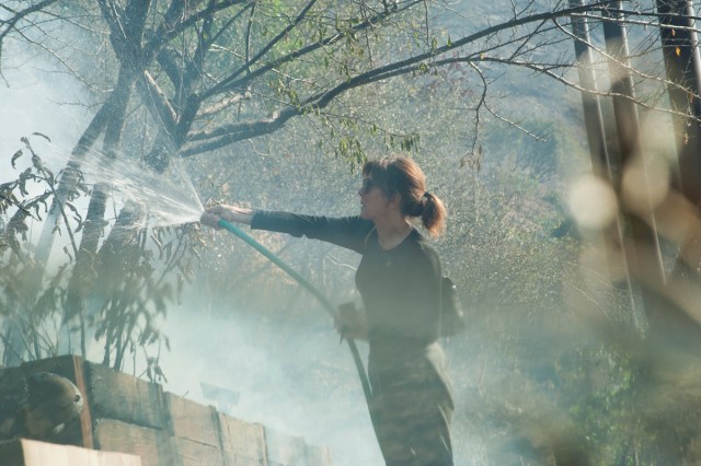 Elizabeth Rawjee sprays water from a garden hose onto hotspots left by the Skirball fire in her backyard on the west side of Los Angeles, California, U.S., December 6, 2017.      REUTERS/Andrew Cullen