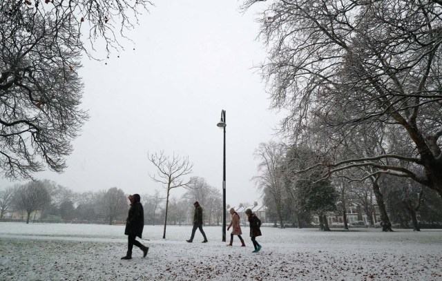 People walk in the first snow to settle in the year in Wanstead, in London, December 10, 2017. REUTERS/Russell Boyce