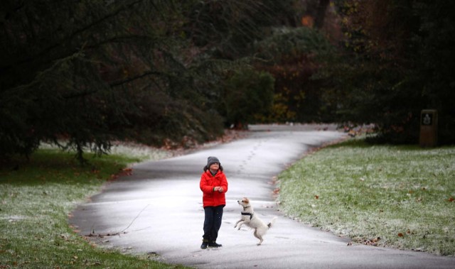 A child plays with a dog in a light dusting of snow in Battersea Park in London, Britain December 10, 2017. REUTERS/Hannah McKay