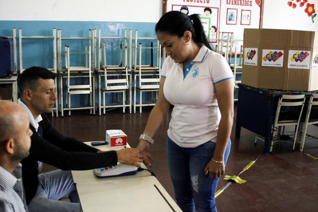 Laidy Gomez (R), governor of Tachira state, places her thumb on an identification machine at a polling station during a nationwide election for new mayors, in Rubio, Venezuela December 10, 2017. REUTERS/Carlos Eduardo Ramirez