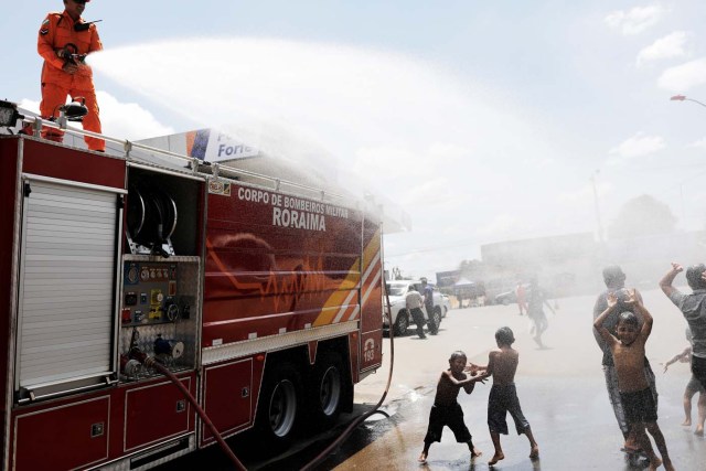 A Brazilian firefighter sprays water to cool Venezuelans outside a gym which has become a shelter for Venezuelans in Boa Vista, Roraima state, Brazil November 18, 2017. REUTERS/Nacho Doce SEARCH "VENEZUELAN MIGRANTS" FOR THIS STORY. SEARCH "WIDER IMAGE" FOR ALL STORIES.