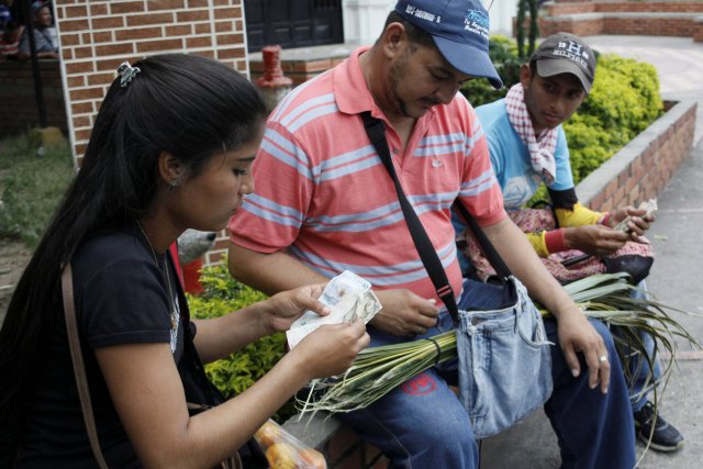 Genesis Materan (L) counts Colombian pesos as she sells vegetables and fruits bought in Venezuela to a customer in Cucuta, Colombia December 15, 2017. Picture taken December 15, 2017. REUTERS/Carlos Eduardo Ramirez