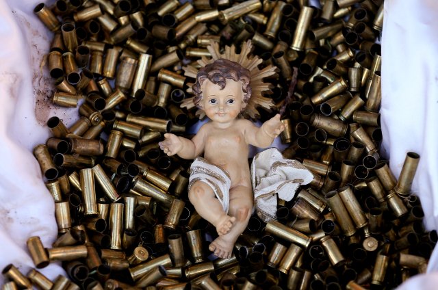 A statue of the baby Jesus on a bed of bullet shells is seen in a Nativity scene outside the Basilica of St Francis in Assisi, Italy, December 21, 2017. The 445 shells represent the number of priests, nuns, monks and religious teachers killed for their faith since 2000. Picture taken December 21, 2017.  REUTERS/Alessandro Bianchi