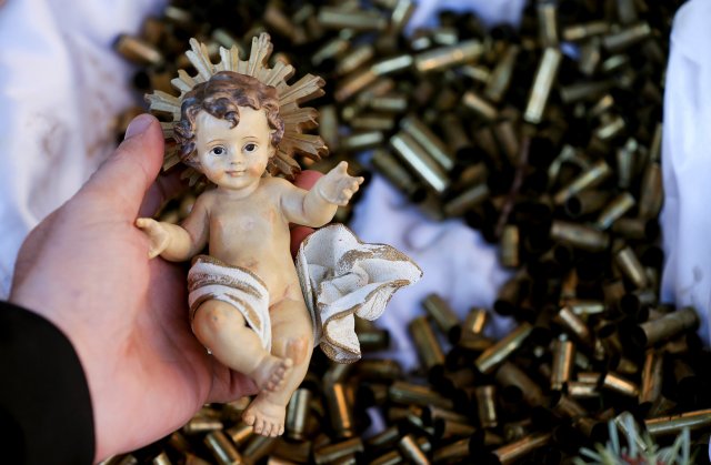 A monk holds a statue of the baby Jesus taken from a bed of bullet shells from a Nativity scene outside the Basilica of St Francis in Assisi, Italy, December 21, 2017. The 445 shells represent the number of priests, nuns, monks and religious teachers killed for their faith since 2000. Picture taken December 21, 2017.  REUTERS/Alessandro Bianchi