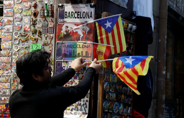 A shop keeper dispays Catalan separatist "Estelada" flags next to souvenirs for tourists at a shop in Barcelona, December 22, 2017. REUTERS/Eric Gaillard
