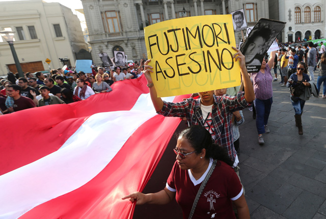 Protesters march as one holds a sign that reads, "Fujimori killer", after Peruvian President Pedro Pablo Kuczynski pardoned former President Alberto Fujimori in Lima, Peru, December 25, 2017. REUTERS/Mariana Bazo