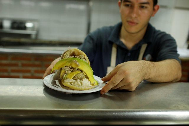 A worker serves an arepa stuffed with cheese, hen salad and avocado at a restaurant in Caracas, Venezuela December 19, 2017. Picture taken December 19, 2017. REUTERS/Marco Bello