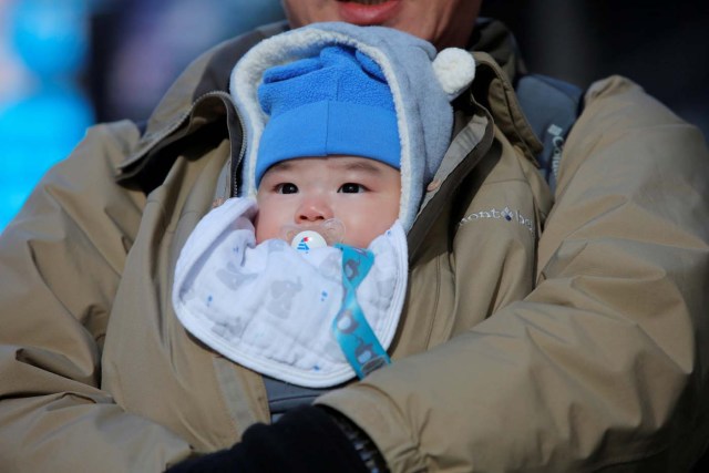 A baby is protected against the cold in Times Square as a cold weather front hits the region in Manhattan, New York, U.S., December 28, 2017. REUTERS/Andrew Kelly