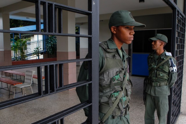 CAR212. CARACAS (VENEZUELA), 10/12/2017.- Integrantes de la Policía Militar venezolana vigilan un centro de votación para las elecciones municipales hoy, domingo 10 de diciembre de 2017, en un puesto de votación en Caracas (Venezuela). Los centros de votación comenzaron a abrir hoy en Venezuela desde las 06.00 hora local (10.00 GMT) para la elección de 335 alcaldes y del gobernador del estado Zulia (oeste), una contienda en la que el grueso de la oposición no participará. EFE/Cristian Hernández