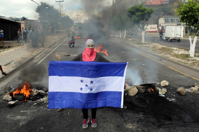 TGP03. TEGUCIGALPA (HONDURAS) 15/12/2017.- Un manifestante posa con la bandera hondureña en frente de una barricada hoy, viernes 15 de diciembre de 2017, en Tegucigalpa (Honduras). Cientos de manifestantes bloquearon hoy importantes carreteras en las principales ciudades de Honduras en protesta por el presunto "fraude" en los comicios del 26 de noviembre contra el candidato de la Alianza de Oposición contra la Dictadura, Salvador Nasralla. EFE/Gustavo Amador
