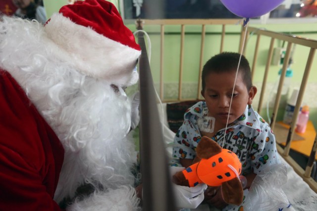 GU301. CIUDAD DE GUATEMALA (GUATEMALA), 20/12/2017.- Santa Claus entrega un regalo a un niño paciente del hospital San Juan de Dios hoy, miércoles 20 de diciembre de 2017, en la ciudad de Guatemala (Guatemala). Santa Claus visitó el segundo hospital público más grande de Guatemala para entregar regalos a los niños, actividad que se ha realizado por 34 años consecutivos. EFE/Esteban Biba