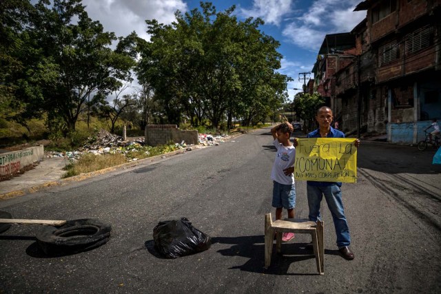 ACOMPAÑA CRÓNICA: VENEZUELA CRISIS. CAR07. CARACAS (VENEZUELA), 27/12/2017.- Un hombre (d) porta un cartel en el que se lee "Fuera de la comuna. No más corrupciión" durante una manifestación hoy, miércoles 27 de diciembre del 2017, en Caracas (Venezuela). Venezuela vive una Navidad con focos de protestas pues en la última semana se han registrado, casi a diario, manifestaciones por falta de "todo" lo que incluye gas doméstico, alimentos y agua, algo que, sumado a la grave crisis económica, ha convertido estas fiestas en "las peores" de los últimos tiempos. EFE/MIGUEL GUTIÉRREZ