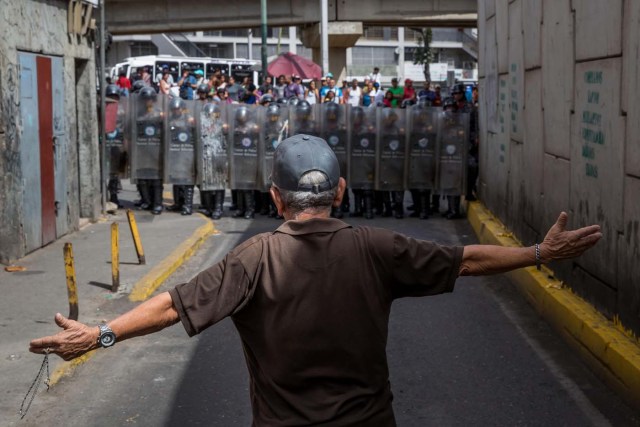 CAR30. CARACAS (VENEZUELA), 28/12/2018.- Un hombre protesta frente a miembros de la Policía Nacional Bolivariana (PNB) hoy, jueves 28 de diciembre del 2017, en Caracas (Venezuela). Las protestas por la escasez, la carestía de alimentos y la falta de gas doméstico y agua continuaron hoy en Caracas y otras ciudades del país, según pudo constatar Efe y de acuerdo con información de medios locales. EFE/MIGUEL GUTIÉRREZ
