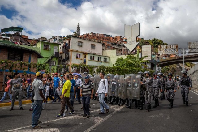 CAR29. CARACAS (VENEZUELA), 28/12/2018.- Un grupo de personas protesta frente a miembros de la Policía Nacional Bolivariana (PNB) hoy, jueves 28 de diciembre del 2017, en Caracas (Venezuela). Las protestas por la escasez, la carestía de alimentos y la falta de gas doméstico y agua continuaron hoy en Caracas y otras ciudades del país, según pudo constatar Efe y de acuerdo con información de medios locales. EFE/MIGUEL GUTIÉRREZ