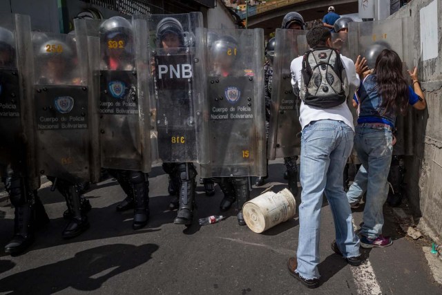 CAR28. CARACAS (VENEZUELA), 28/12/2018.- Un grupo de personas protesta frente a miembros de la Policía Nacional Bolivariana (PNB) hoy, jueves 28 de diciembre del 2017, en Caracas (Venezuela). Las protestas por la escasez, la carestía de alimentos y la falta de gas doméstico y agua continuaron hoy en Caracas y otras ciudades del país, según pudo constatar Efe y de acuerdo con información de medios locales. EFE/MIGUEL GUTIÉRREZ