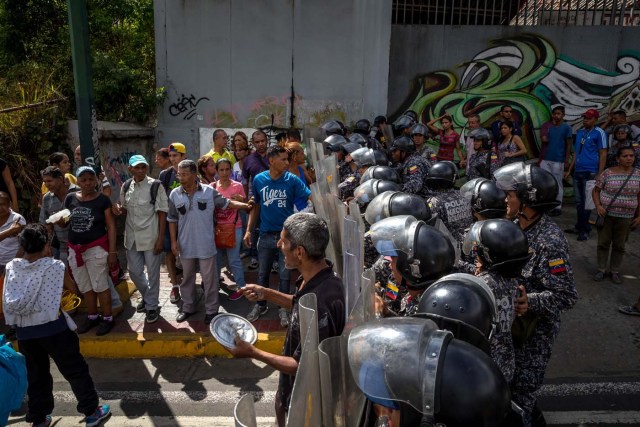 CAR26. CARACAS (VENEZUELA), 28/12/2018.- Un grupo de personas protesta frente a miembros de la Policía Nacional Bolivariana (PNB) hoy, jueves 28 de diciembre del 2017, en Caracas (Venezuela). Las protestas por la escasez, la carestía de alimentos y la falta de gas doméstico y agua continuaron hoy en Caracas y otras ciudades del país, según pudo constatar Efe y de acuerdo con información de medios locales. EFE/MIGUEL GUTIÉRREZ