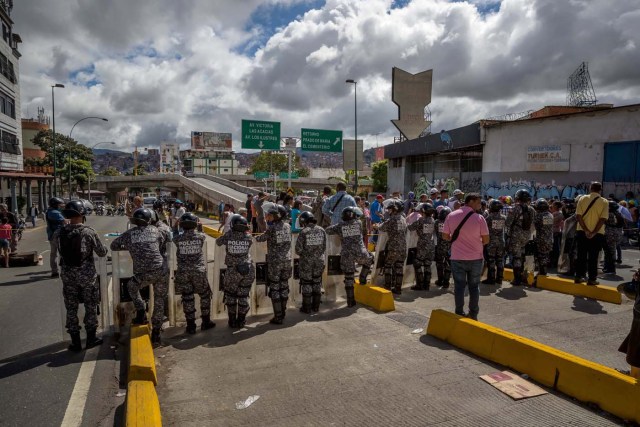 CAR23. CARACAS (VENEZUELA), 28/12/2018.- Un grupo de personas protesta frente a miembros de la Policía Nacional Bolivariana (PNB) hoy, jueves 28 de diciembre del 2017, en Caracas (Venezuela). Las protestas por la escasez, la carestía de alimentos y la falta de gas doméstico y agua continuaron hoy en Caracas y otras ciudades del país, según pudo constatar Efe y de acuerdo con información de medios locales. EFE/MIGUEL GUTIÉRREZ