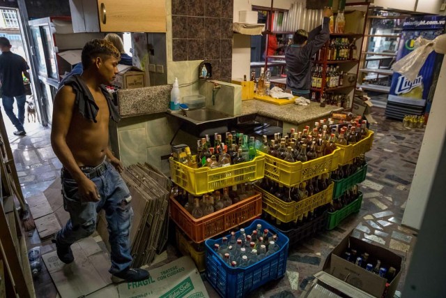 CAR105. CARACAS (VENEZUELA), 28/12/2018.- Un trabajador de una licorera que fue saqueada en horas de la madrugada en el sector La Vega saca productos del local comercial hoy, jueves 28 de diciembre del 2017, en Caracas (Venezuela). Durante la madrugada de este jueves se registraron en varios puntos de Venezuela protestas por la escasez de alimentos para completar el menú navideño, gas y agua, informaron hoy medios locales. EFE/MIGUEL GUTIÉRREZ