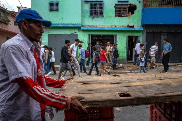 CAR104. CARACAS (VENEZUELA), 28/12/2018.- Un grupo de personas caminan frente a una licorera que fue saqueada en horas de la madrugada en el sector La Vega hoy, jueves 28 de diciembre del 2017, en Caracas (Venezuela). Durante la madrugada de este jueves se registraron en varios puntos de Venezuela protestas por la escasez de alimentos para completar el menú navideño, gas y agua, informaron hoy medios locales. EFE/MIGUEL GUTIÉRREZ