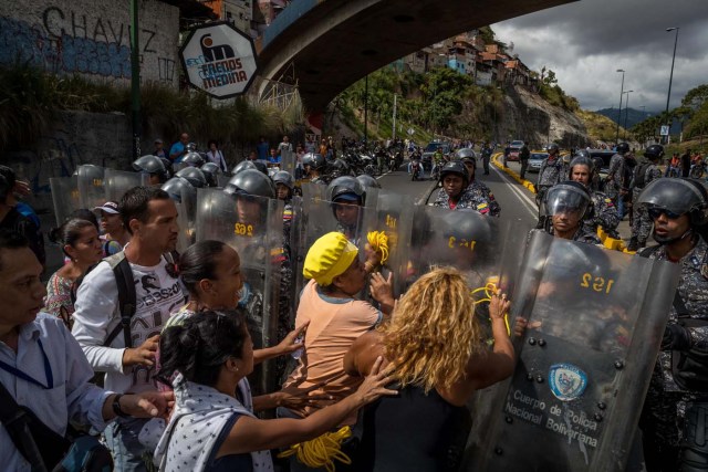 -FOTODELDÍA- CAR25. CARACAS (VENEZUELA), 28/12/2018.- Un grupo de personas protesta frente a miembros de la Policía Nacional Bolivariana (PNB) hoy, jueves 28 de diciembre del 2017, en Caracas (Venezuela). Las protestas por la escasez, la carestía de alimentos y la falta de gas doméstico y agua continuaron hoy en Caracas y otras ciudades del país, según pudo constatar Efe y de acuerdo con información de medios locales. EFE/MIGUEL GUTIÉRREZ