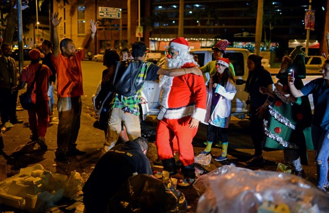 A man dressed as Santa Claus talks to homeless during the event "Santa en las calles" in the streets of Caracas on December 16, 2017. "Santa in the Streets" is a non-governmental non-profit organization whose goal is to bring Christmas to needy people in the popular areas of Caracas. / AFP PHOTO / FEDERICO PARRA / TO GO WITH AFP STORY by Alex VASQUEZ