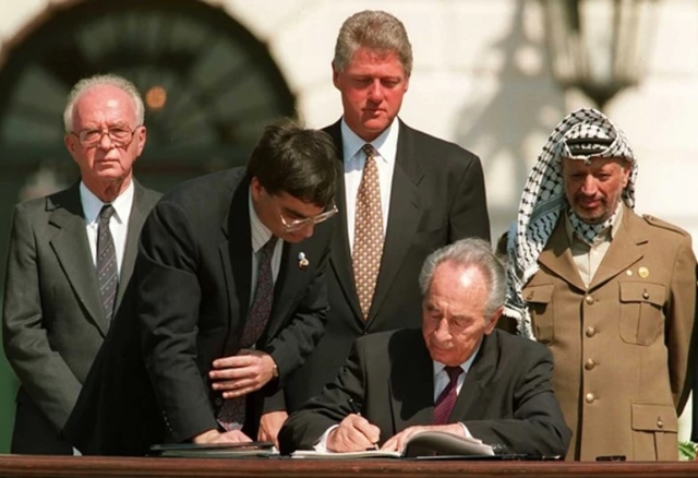 Shimon Peres firma los acuerdos de Oslo. Detrás: Isaac Rabin, Bill Clinton y Yaser Arafat (AFP)
